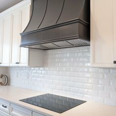 a stove top oven sitting inside of a kitchen next to white cabinets and counter tops