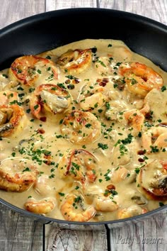 a skillet filled with shrimp and grits on top of a wooden table,