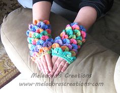 a person wearing colorful crocheted gloves on their hands