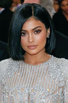 a woman with black hair wearing a silver dress and diamond jewelry on the red carpet