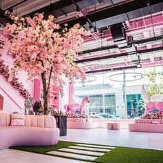 a room with pink couches and flowers on the wall, in front of a staircase