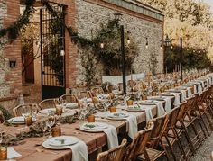 a long table is set with plates and place settings for an outdoor dinner party outside