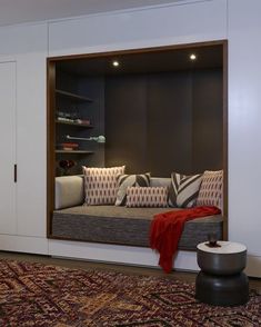 a living room with a couch, rug and shelves in the wall behind it that have pillows on them