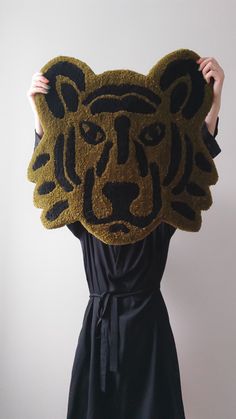 a woman is holding up a rug with a tiger head on it's face