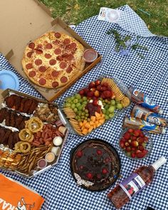 a table topped with lots of food and pizza on top of a blue checkered cloth