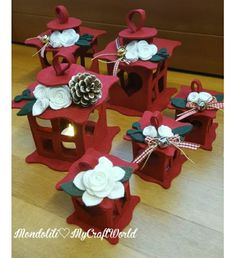 four red birdhouses decorated with white flowers and pineconis are sitting on a wooden floor