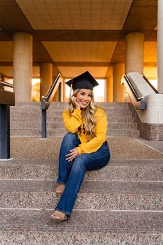 a woman sitting on some steps wearing a graduation cap