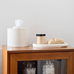 a wooden cabinet with two jars and a white container on top