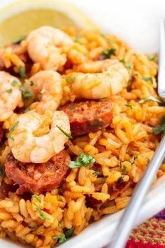 a bowl filled with rice and shrimp on top of a table next to a fork