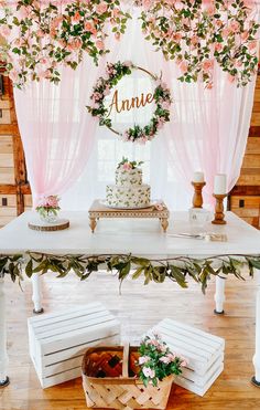 the table is decorated with pink flowers and greenery for an elegant wedding cake display