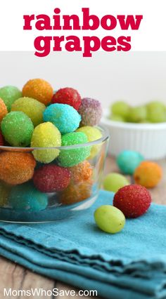 a bowl filled with rainbow colored gummy balls on top of a blue cloth next to bowls