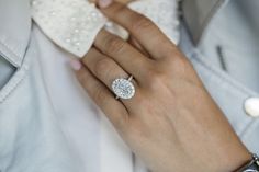 a woman's hand with a diamond ring on her left wrist and a white bowtie around her neck