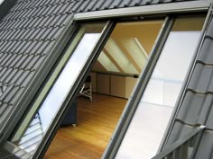 an open window on the side of a building with wood floors and metal roofing