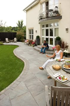 two people are sitting on the back patio eating and having lunch with their friends outside