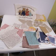 several pieces of cloth and paper on a table with teddy bears in the background,