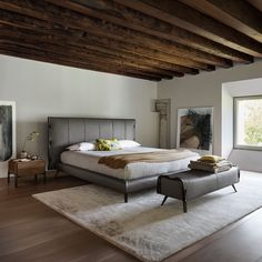 a bedroom with a large bed sitting on top of a wooden floor next to a window