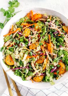 a salad in a white bowl with oranges and shredded lettuce on the side