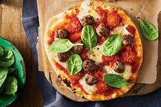 a pizza sitting on top of a wooden cutting board next to green plates and utensils