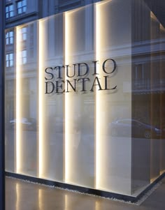 a glass window with the words studio dental on it's side and an illuminated building in the background