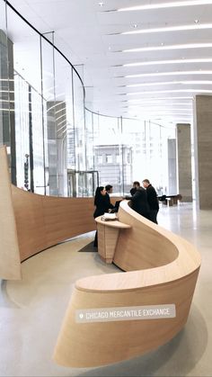 two people sitting at a table in an office lobby with curved wooden bench and glass walls