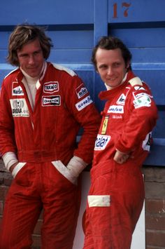 two men standing next to each other in red racing suits