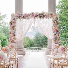 an outdoor wedding venue with white and pink flowers on the aisle, decorated in gold chairs