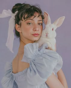 a woman in a blue dress holding a rabbit on her shoulder and looking at the camera