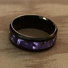 a black and purple wedding band on top of a table