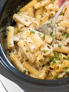 a crock pot filled with macaroni and cheese being stirred with a spoon