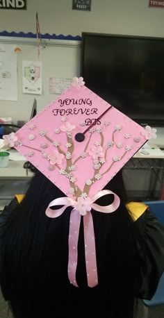 a woman wearing a pink graduation cap with flowers on it's side and writing