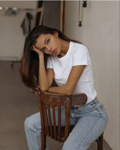 a beautiful young woman sitting on top of a wooden chair