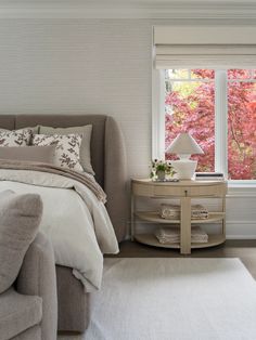 a bedroom with white walls and carpeted flooring, along with a bed in front of a large window