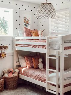 a bedroom with bunk beds and pillows on the bottom bunk, next to a basket full of stuffed animals