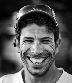 a smiling man with a baseball cap on his head and no teeth is seen in this black and white photo