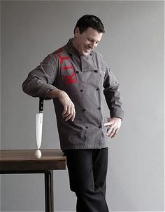 a man in a chef's coat standing next to a table with an umbrella