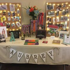 a table topped with pictures and decorations on top of a white tablecloth covered in lights