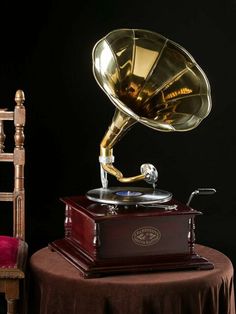 an old fashioned record player sitting on top of a table next to a wooden chair