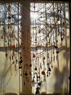 a window with beads hanging from it's side and the sun shining in through