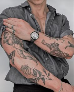 a man with tattoos on his arm and wrist is posing for the camera while wearing a black shirt