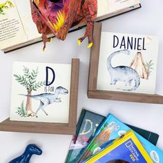 three children's books with dinosaurs on them and an animal figurine next to them