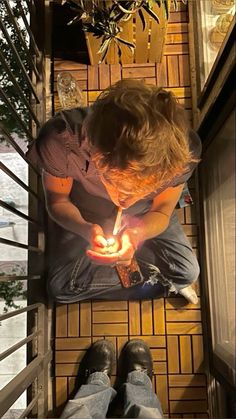 a man sitting on the floor lighting a candle