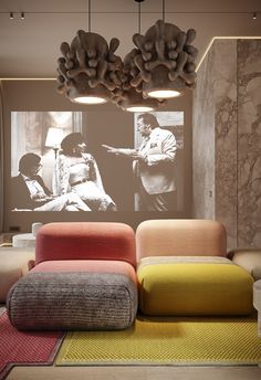 a living room filled with lots of different colored furniture and lighting fixture hanging from the ceiling