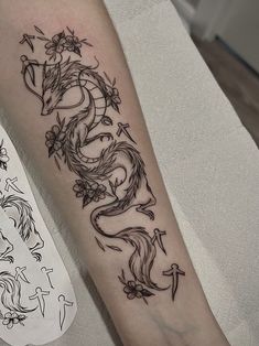 a tattoo on the arm of a woman with an arrow and dragon design in black ink