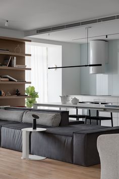 a living room filled with furniture next to a kitchen and dining room table in front of a bookshelf