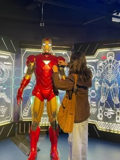 two people standing in front of a display of iron man armor