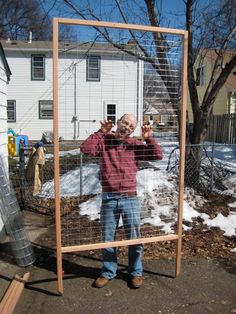 a man standing in front of a cage holding up two fingers to the side with one hand