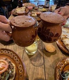 two people are toasting over some food at a table with plates and cups on it