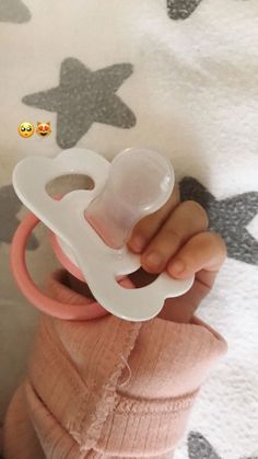 a baby holding a pacifier in it's hand