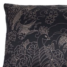 a black pillow with white flowers and birds on it