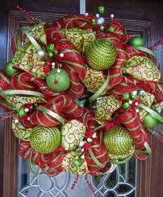 a christmas wreath with ornaments hanging from it's side on a front door window